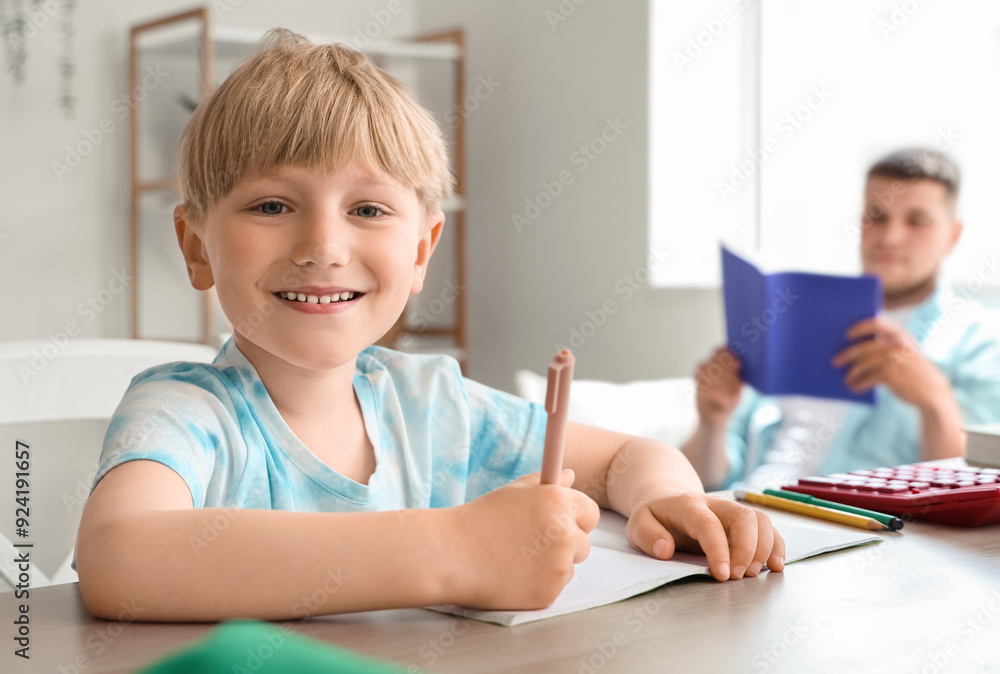 Cute boy taking dictation by his father in room Cute boy taking dictation by his father in room