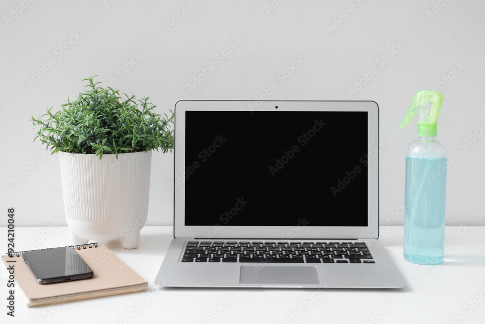 Bottle of aroma spray with blank computer on table in room Bottle of aroma spray with blank computer on table in room