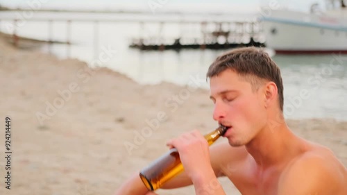 Male gay couple shirtless having fun drinking beer at tropical beach near pier during vacation. Slow motion. photo