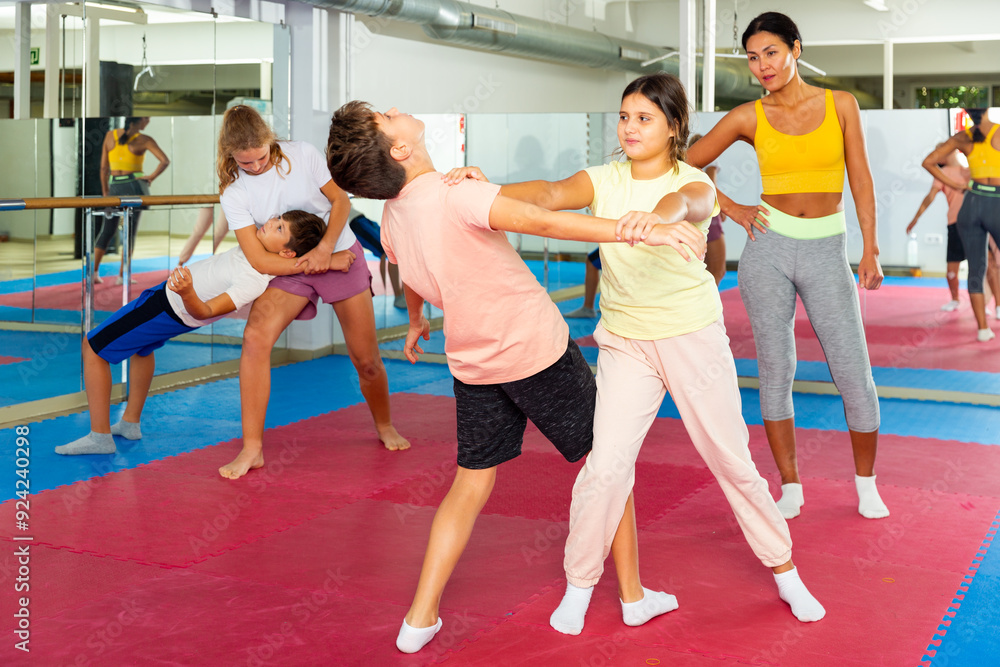 Obraz premium Young children working in pair mastering new self-defense moves at gym during group class