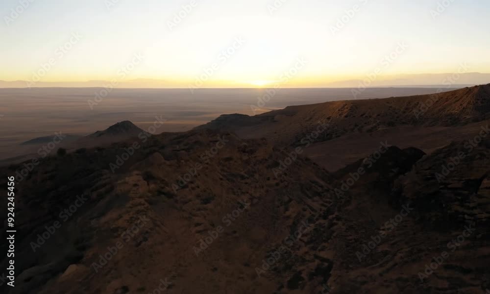 Drone shot of the Mutla Ridge in Kuwait, with the camera moving along the ridge at dawn, capturing the panoramic views of the arid landscape and the subtle changes in the terrain as the light shifts. Drone shot of the Mutla Ridge in Kuwait, with the camera moving along the ridge at dawn, capturing the panoramic views of the arid landscape and the subtle changes in the terrain as the light shifts.