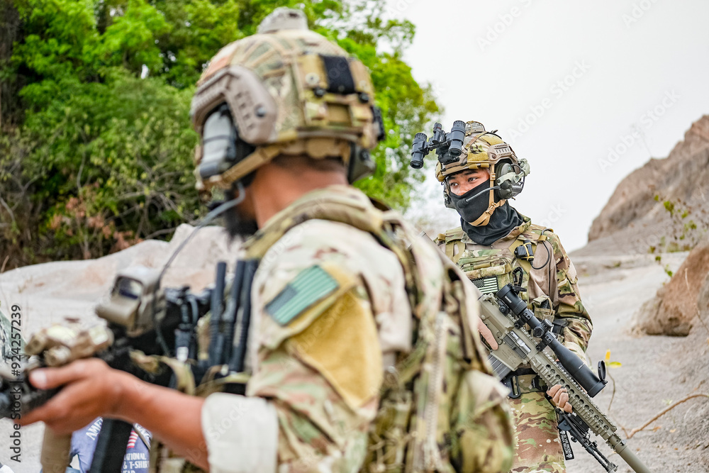 Fototapeta premium A group of military men in combat gear patrol in the middle of a desert and tropical jungle. Soldiers in full combat gear in dry weather conditions assemble and march on a mission.