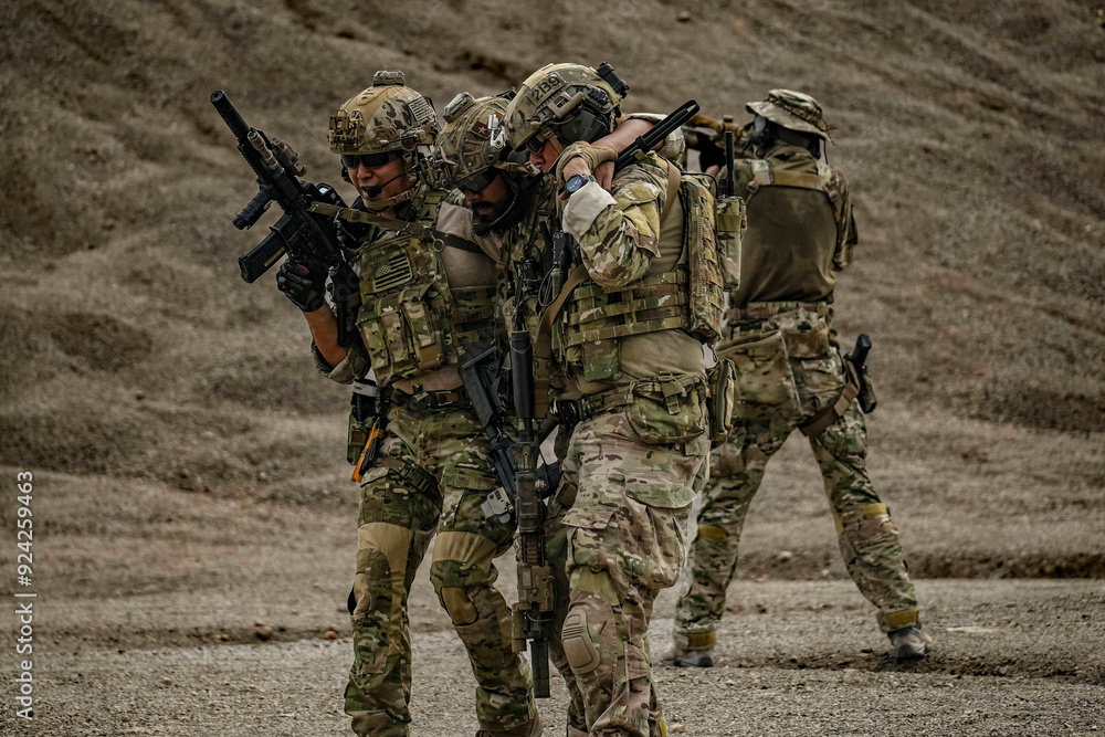 Fototapeta premium A group of military men in combat gear patrol in the middle of a desert and tropical jungle. Soldiers in full combat gear in dry weather conditions assemble and march on a mission.