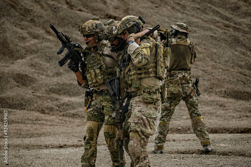 A group of military men in combat gear patrol in the middle of a desert and tropical jungle. Soldiers in full combat gear in dry weather conditions assemble and march on a mission.