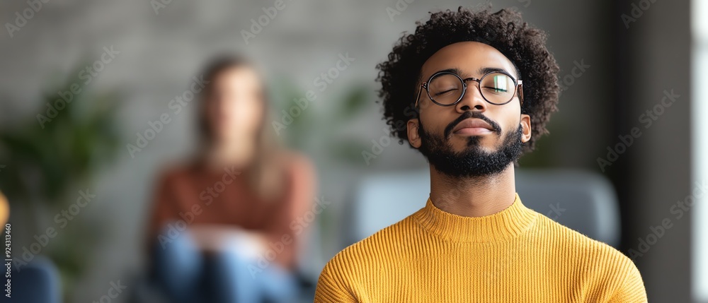 Young man with glasses practicing mindfulness meditation indoors. Calm and focused in serene setting with blurred background. Young man with glasses practicing mindfulness meditation indoors. Calm and focused in serene setting with blurred background.