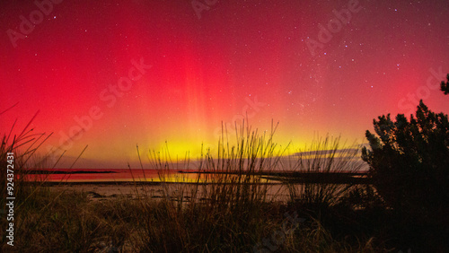 Obraz na plátně Colorful aurora australis lights up sky over beach.