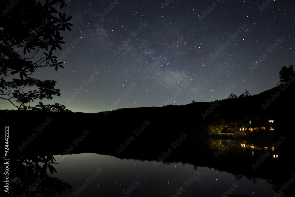 Naklejka premium 山奥の樹々の先にある池に映る星と天の川