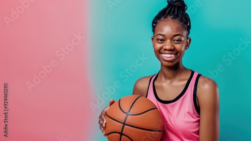 A young girl joyfully holds a basketball, showcasing her passion for the sport against a vibrant background photo