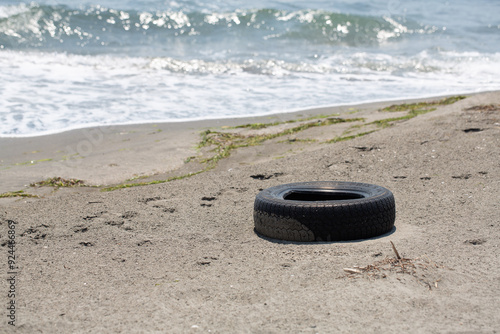 Old washed up tire polluting a sandy beach