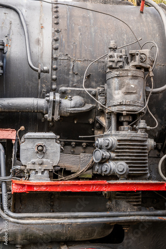 Detail of an old rusty steam train engine with intricate machinery and weathered metal components