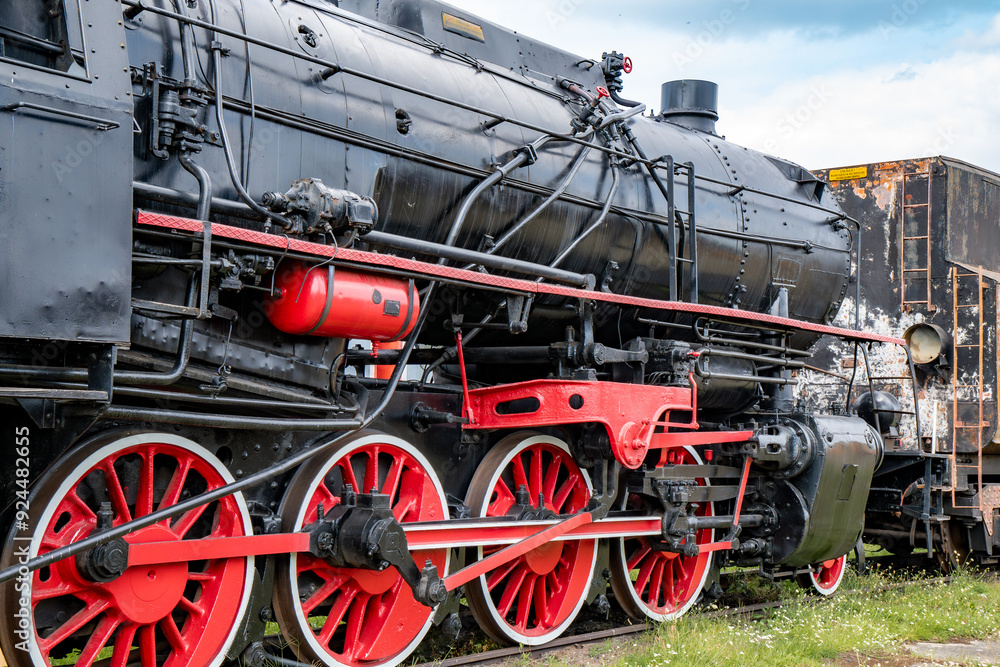 Obraz premium Rusty old steam train showcasing intricate details at a historic railway site on a cloudy afternoon