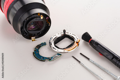 A broken lens of a professional camera and repair tools on a white table. 