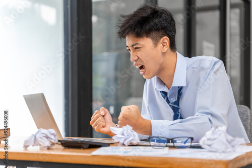 Frustrated and angry young businessman working late at the office trying to finish his project