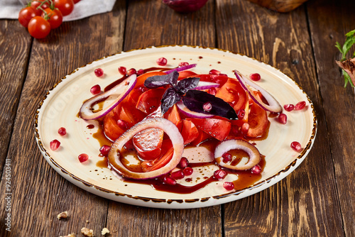 Fresh Tomato Salad with Red Onion and Narsharab Sauce on Wooden Rustic Background photo