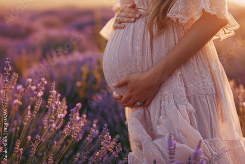 A expecting mother stands amidst purple blooms, ideal for maternity or nature-themed projects #924516265