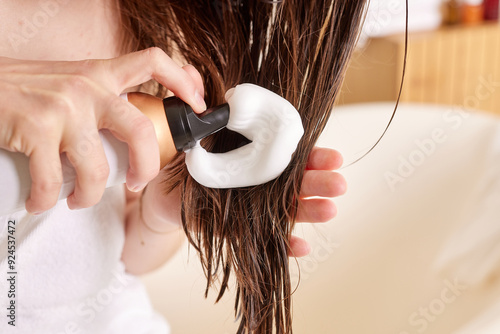 Konstfotografi girl applying hair foam on wet hair after shower, hair care concept