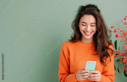 Young Woman Smiling While Texting on Smartphone Against Green Background