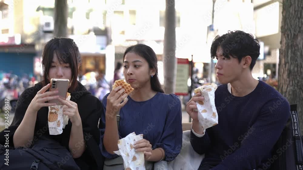 In Taipei's Da'an District, a slow-motion video captures a group of students in their twenties, Taiwanese men and women and a South Asian woman, sitting together on a street bench enjoying waffles. In Taipei's Da'an District, a slow-motion video captures a group of students in their twenties, Taiwanese men and women and a South Asian woman, sitting together on a street bench enjoying waffles.