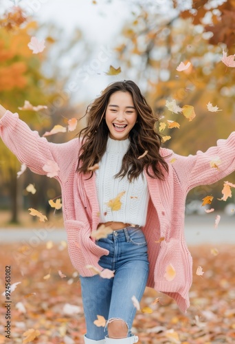 Joyful Woman Playing With Autumn Leaves in a Park During a Sunny Fall Day