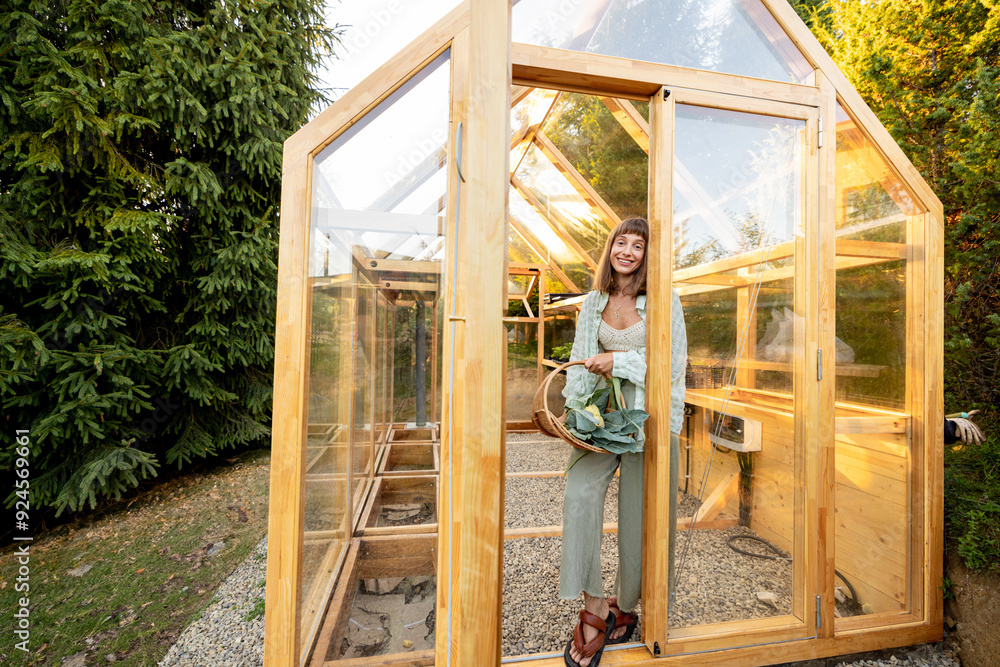 Smiling woman holding a basket filled with freshly harvested cauliflower, standing at the entrance of a wooden greenhouse Smiling woman holding a basket filled with freshly harvested cauliflower, standing at the entrance of a wooden greenhouse