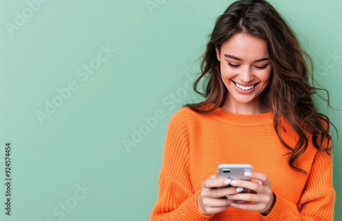 Young Woman Smiling While Texting on Smartphone Against Green Background