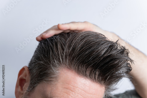 Close-up of an unrecognizable man combing his toupee with his hand. Styling and hair care concept