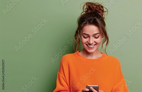 Young Woman Smiling While Texting on Smartphone Against Green Background