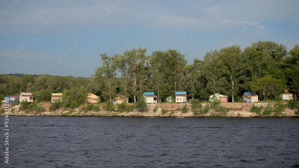 Panning shot of scenic riverside cabins surrounded by lush green trees. Russia, Samara Panning shot of scenic riverside cabins surrounded by lush green trees. Russia, Samara