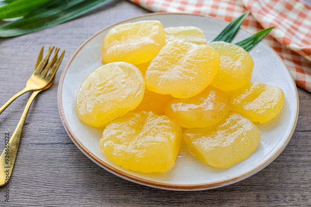Toddy palm in syrup in a white ceramic with golden fork plate on wooden background , thai dessert , thai called luk tan chuem Toddy palm in syrup in a white ceramic with golden fork plate on wooden background , thai dessert , thai called luk tan chuem