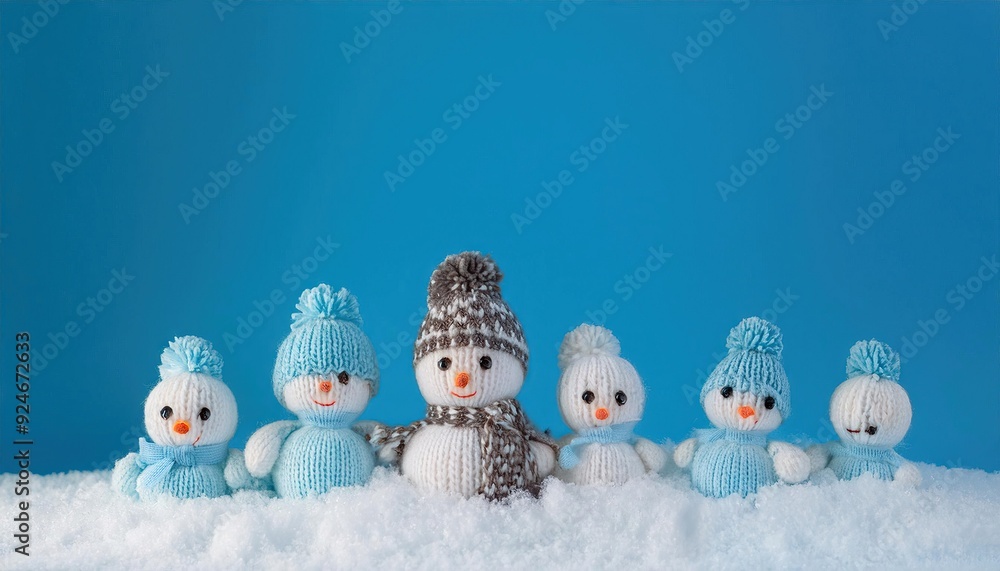 little knitted snowmans on soft snow on blue background little knitted snowmans on soft snow on blue background