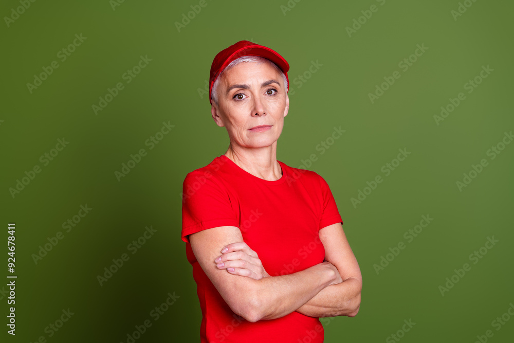 Fototapeta premium Photo of attractive mature woman delivery employee crossed arms cheerful smile wear red uniform workwear isolated on khaki color background