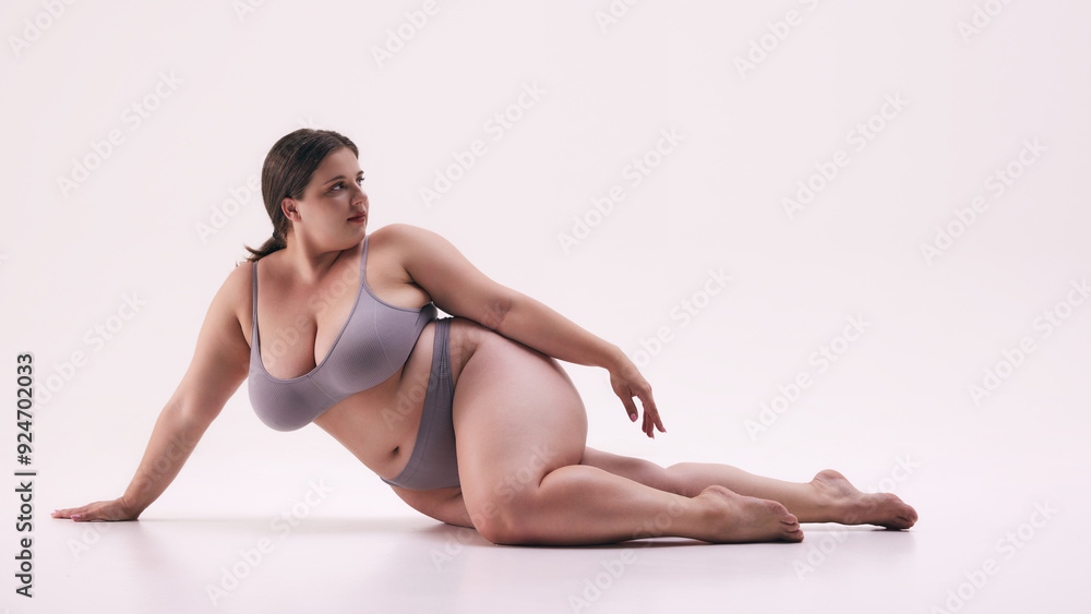 Strong woman, plus size model wearing underwear, posing lying on floor, show her body with pride against white studio background. Concept of natural beauty, body positivity, self love, treatments. Ad Strong woman, plus size model wearing underwear, posing lying on floor, show her body with pride against white studio background. Concept of natural beauty, body positivity, self love, treatments. Ad