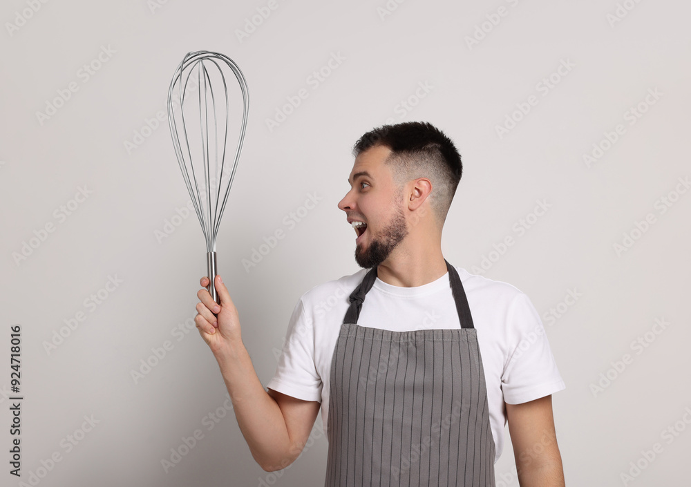 Emotional pastry chef with big whisk on light grey background Emotional pastry chef with big whisk on light grey background