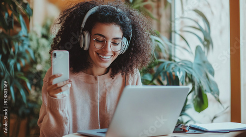 Person with headphones, laptop and smartphone.