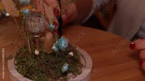 Female hand decorating a miniature floral arrangement