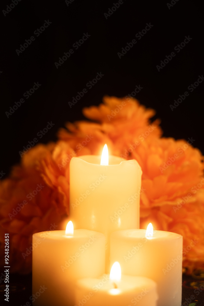 Vertical image showing three candles burning brightly, surrounded by marigold flowers Vertical image showing three candles burning brightly, surrounded by marigold flowers