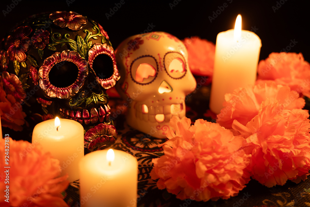 Skulls on a Día de los Muertos cloth—one with a metallic floral design, the other hollow with a candle
