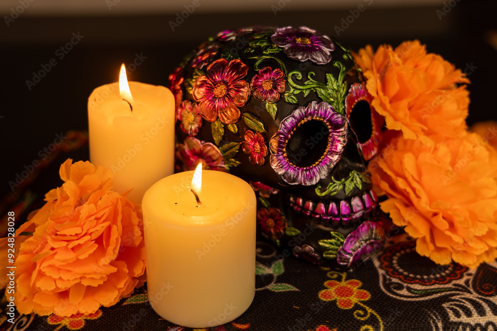 A skull intricately decorated with metal flowers and surrounded by bright orange marigolds. The scene is completed with two flickering candles A skull intricately decorated with metal flowers and surrounded by bright orange marigolds. The scene is completed with two flickering candles