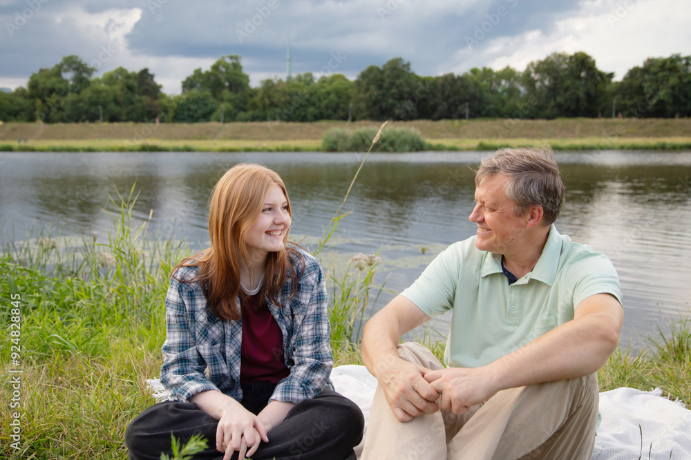 father and teenage daughter relaxing together outdoors in summer father and teenage daughter relaxing together outdoors in summer