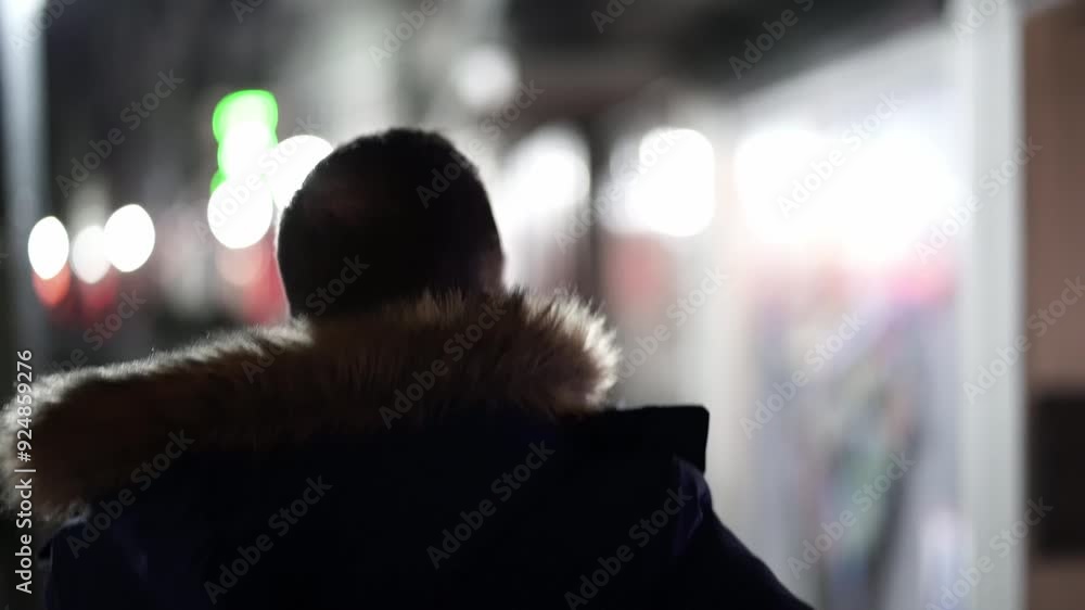 Mann geht nachts mit Jacke die Strasse entlang Mann geht nachts mit Jacke die Strasse entlang
