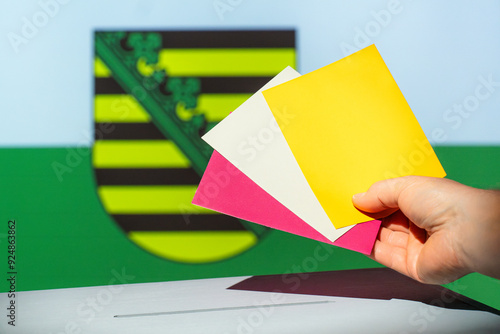 Voting envelope is put into the ballot box for the state election in Saxony. Various envelopes or parties to choose from. Flag of Saxony in the background. Election year 2024 in Germany. photo