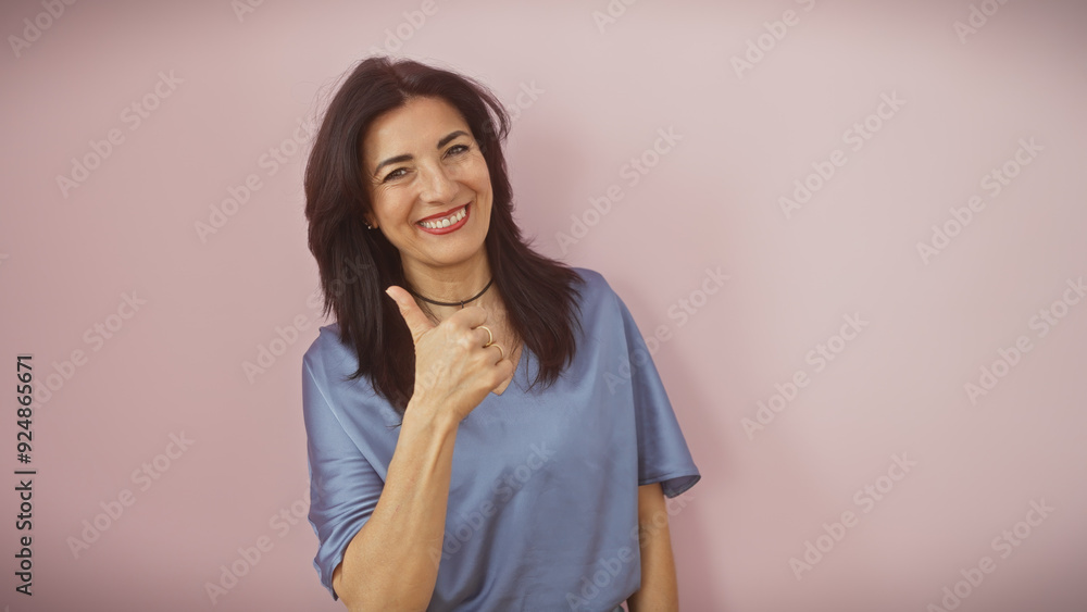 Smiling mature hispanic woman giving thumbs up isolated on a pink background Smiling mature hispanic woman giving thumbs up isolated on a pink background