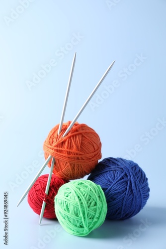 Colorful yarns and knitting needles on light background