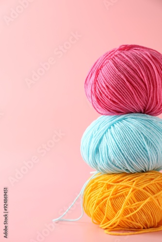 Stack of colorful yarns on pink background. Space for text