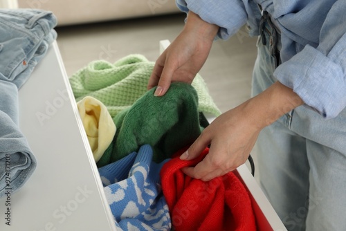 Fotografie Woman organizing clothes in chest of drawers indoors, closeup