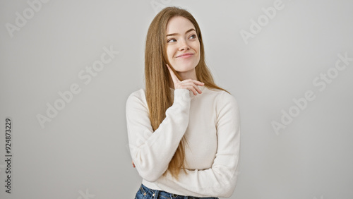 A thoughtful young caucasian woman with blonde hair wearing a sweater isolated against a white background, exuding beauty and youth.