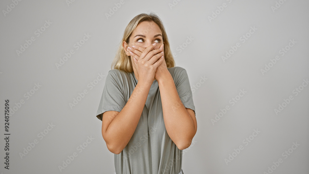 A surprised young caucasian woman covers her mouth with hands against a white wall, embodying beauty and expression. A surprised young caucasian woman covers her mouth with hands against a white wall, embodying beauty and expression.