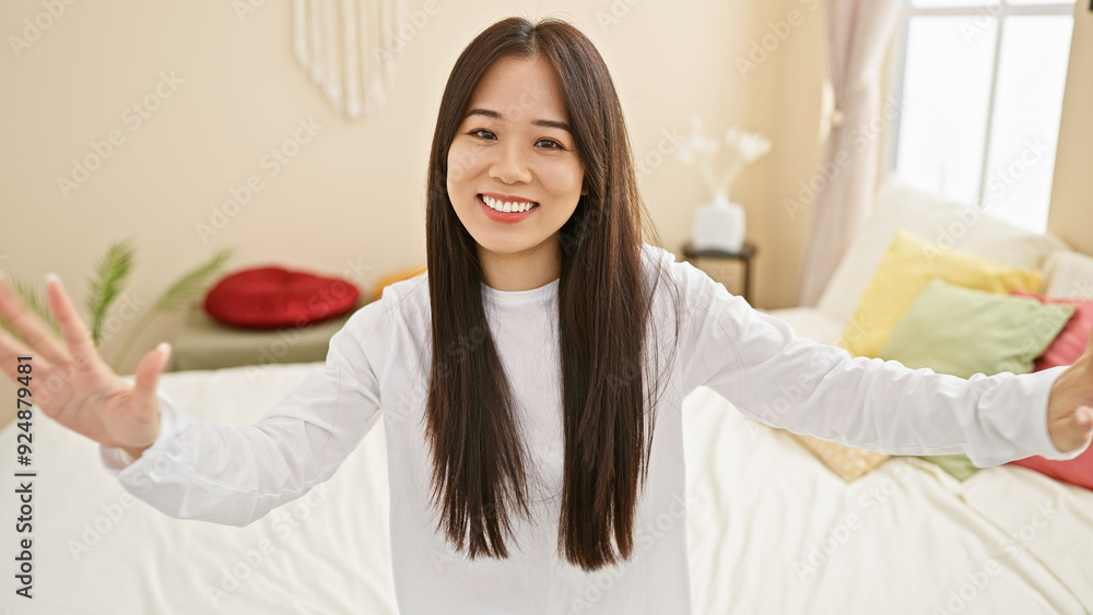 Smiling asian woman welcoming in a bright cozy bedroom Smiling asian woman welcoming in a bright cozy bedroom