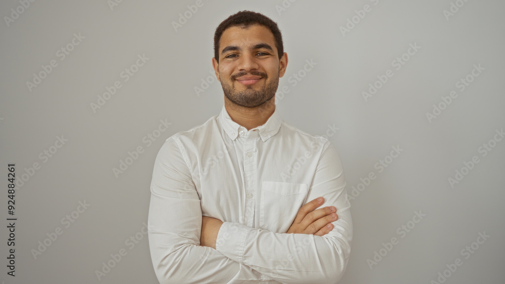 Handsome young man smiling confidently with arms crossed against isolated white background Handsome young man smiling confidently with arms crossed against isolated white background
