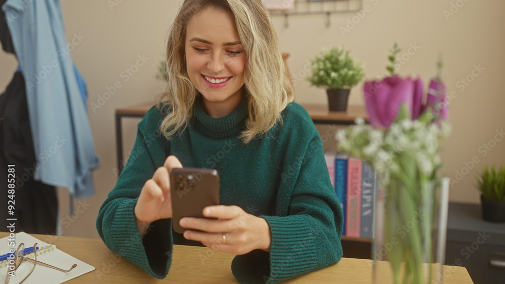Smiling caucasian woman using smartphone in a cozy home interior with flowers and books.
